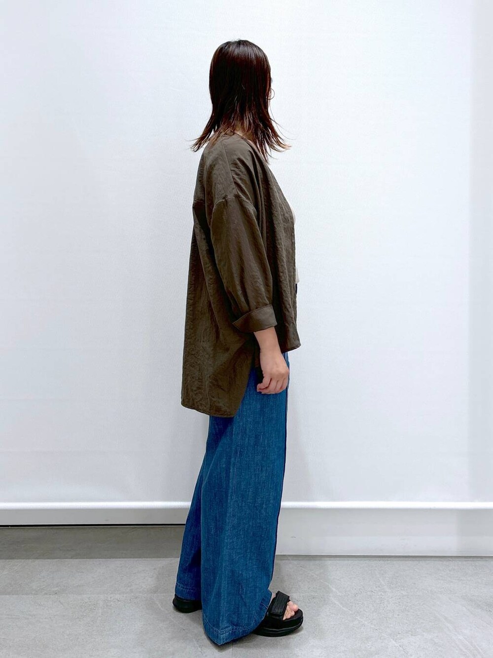 ブルー系のデニムパンツ、ブラック系のサンダル、ブラック系のハンドバッグを着用したレディースの夏コーディネートの5枚目の写真