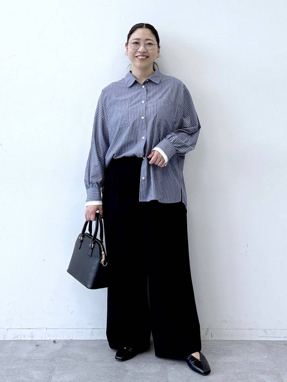 ブラック系のハンドバッグ、ブラック系のパンプス、ブルー系のシャツ/ブラウスを着用したレディースの冬コーディネートの2枚目の写真