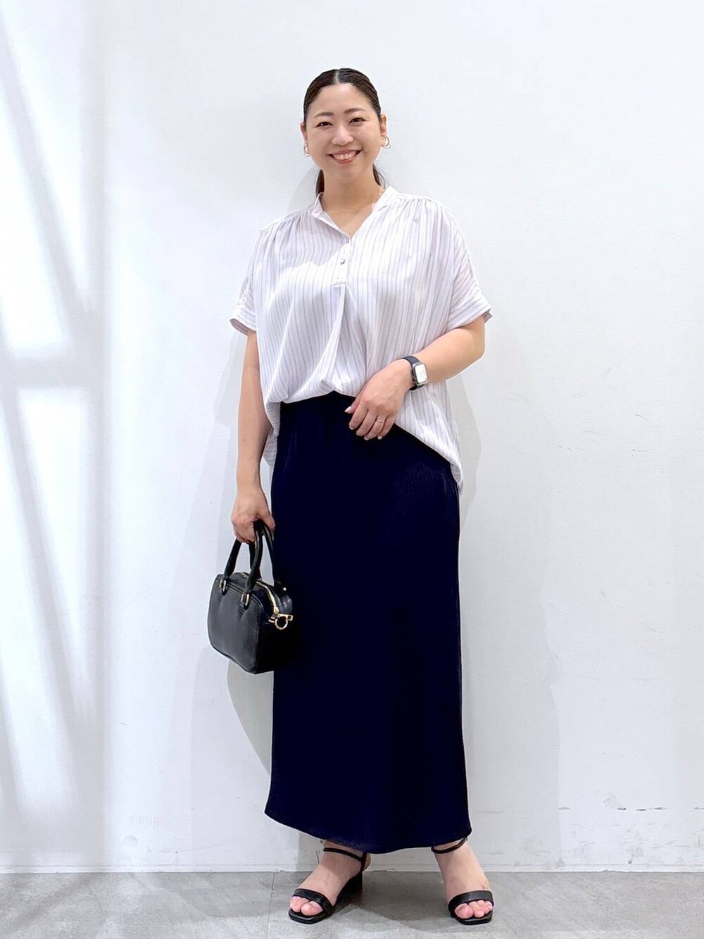 ブルー系のスカート、ブラック系のハンドバッグ、ブルー系のシャツ/ブラウスを着用したレディースの夏コーディネートの2枚目の写真