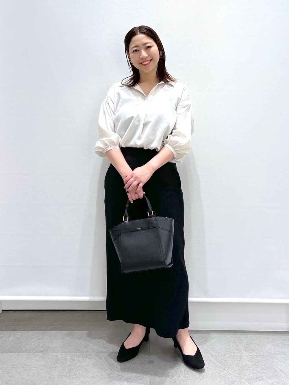 ホワイト系のTシャツ/カットソー、ブラック系のハンドバッグ、ブラック系のパンプスを着用したレディースの春コーディネートの2枚目の写真