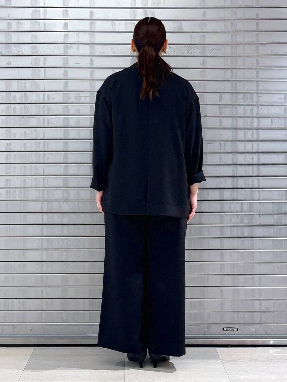 ブラック系のハンドバッグ、ホワイト系のベストを着用したレディースの春コーディネートの4枚目の写真