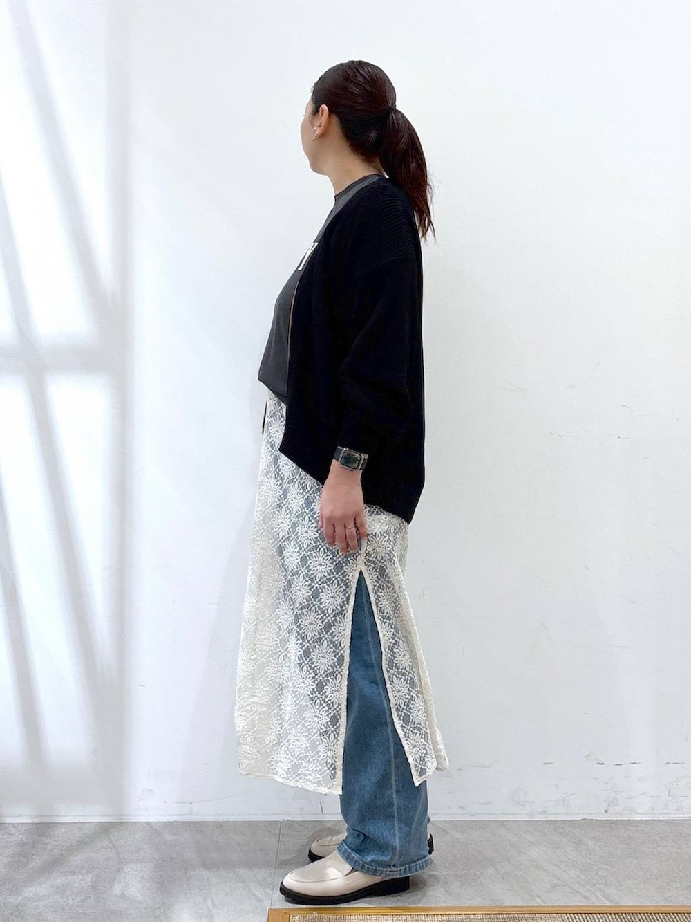 ホワイト系のワンピース、ホワイト系のハンドバッグ、ブルー系のデニムパンツを着用したレディースの春コーディネートの3枚目の写真