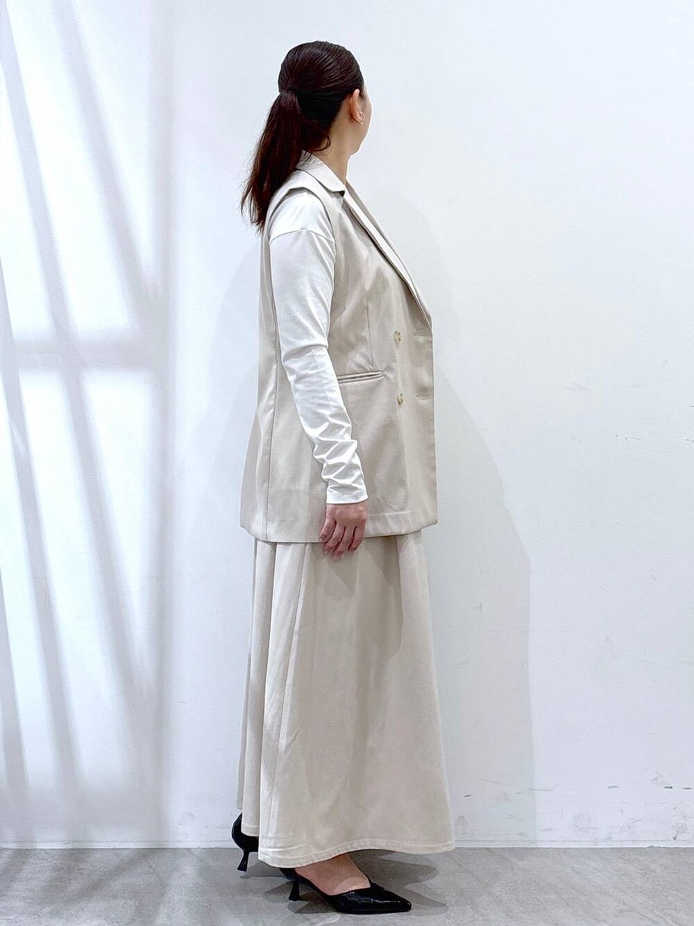 ベージュ系のスカート、ベージュ系のベスト、ホワイト系のTシャツ/カットソーを着用したレディースの春コーディネートの5枚目の写真