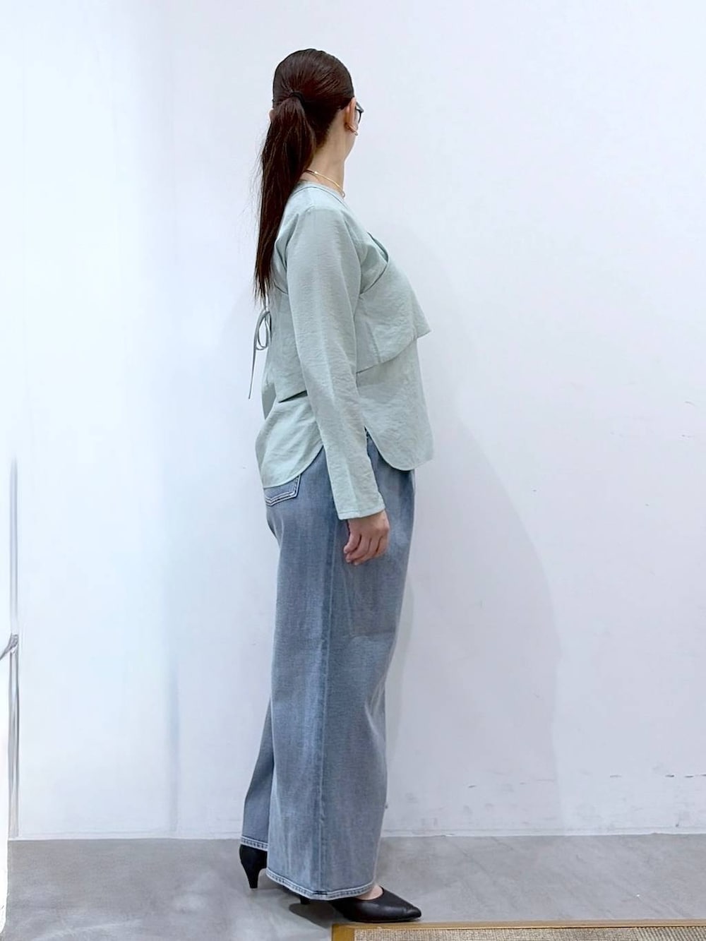 ブルー系のデニムパンツ、ブラック系のハンドバッグ、グリーン系のシャツ/ブラウスを着用したレディースの春コーディネートの5枚目の写真