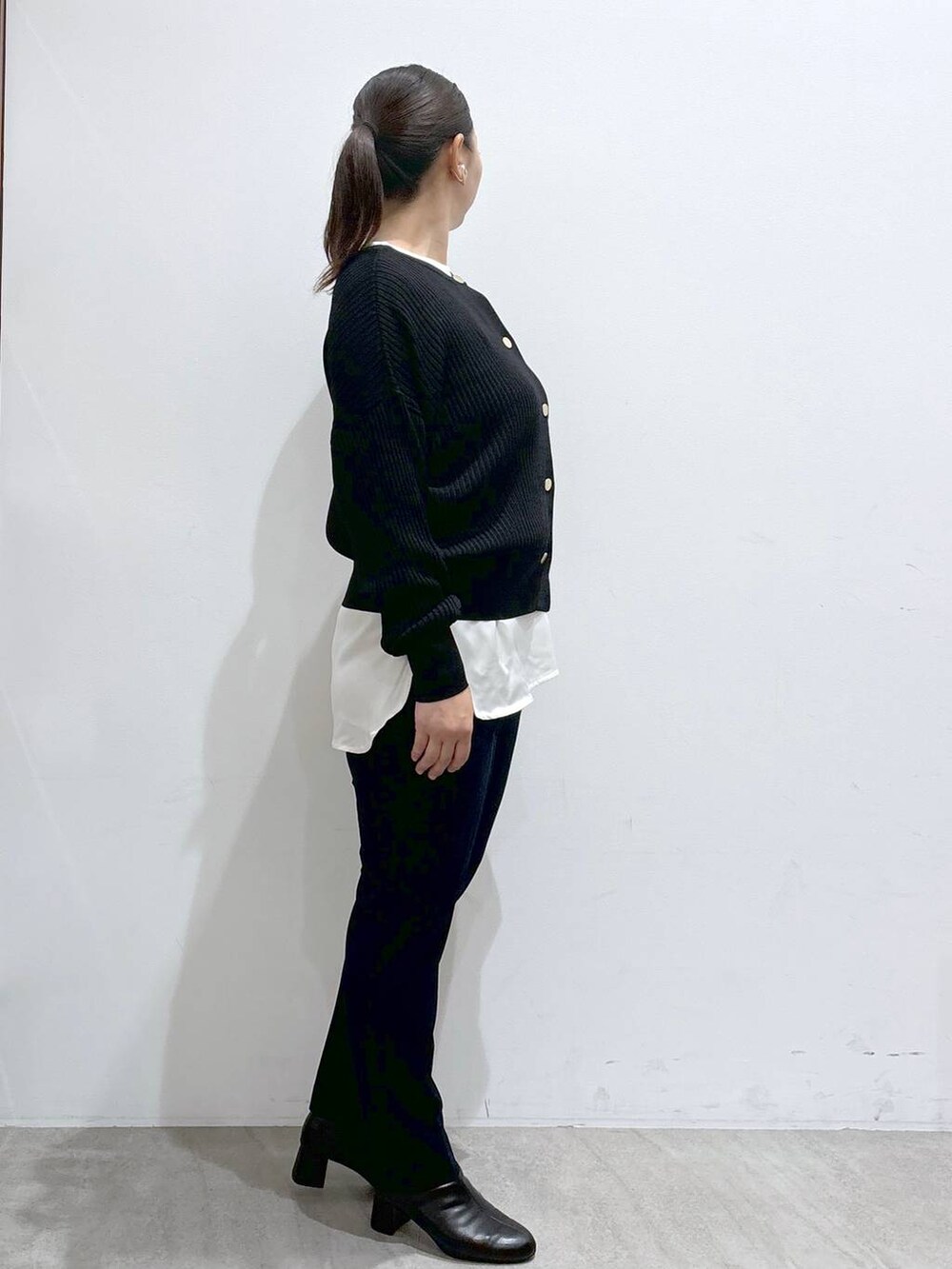 ブラック系のカーディガン/ボレロ、ブラック系のハンドバッグ、ブラック系のブーツを着用したレディースの秋コーディネートの5枚目の写真