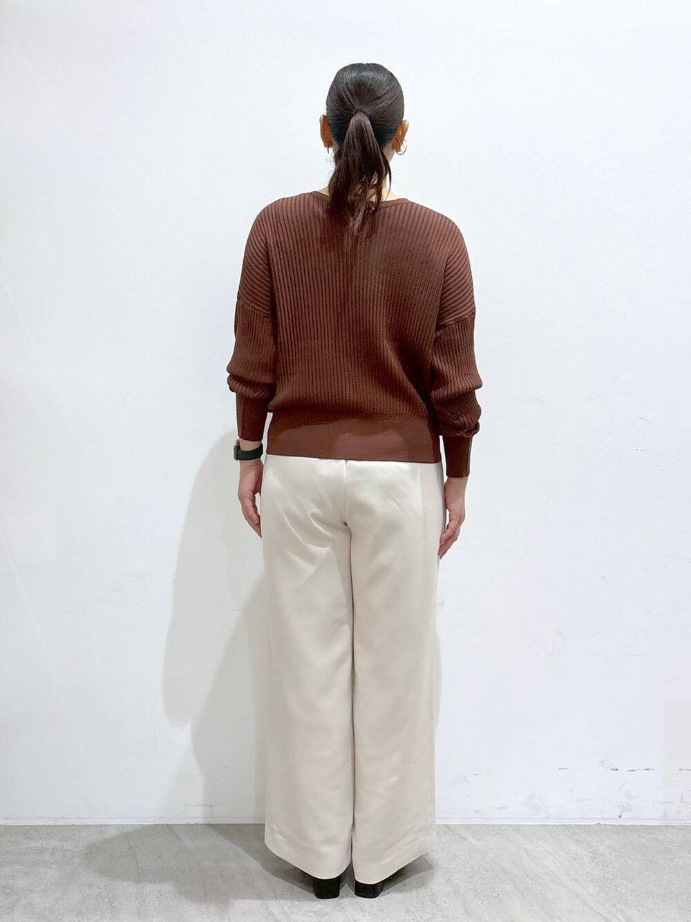 ブラウン系のカーディガン/ボレロ、ブラック系のブーツ、ブラウン系のハンドバッグを着用したレディースの秋コーディネートの4枚目の写真