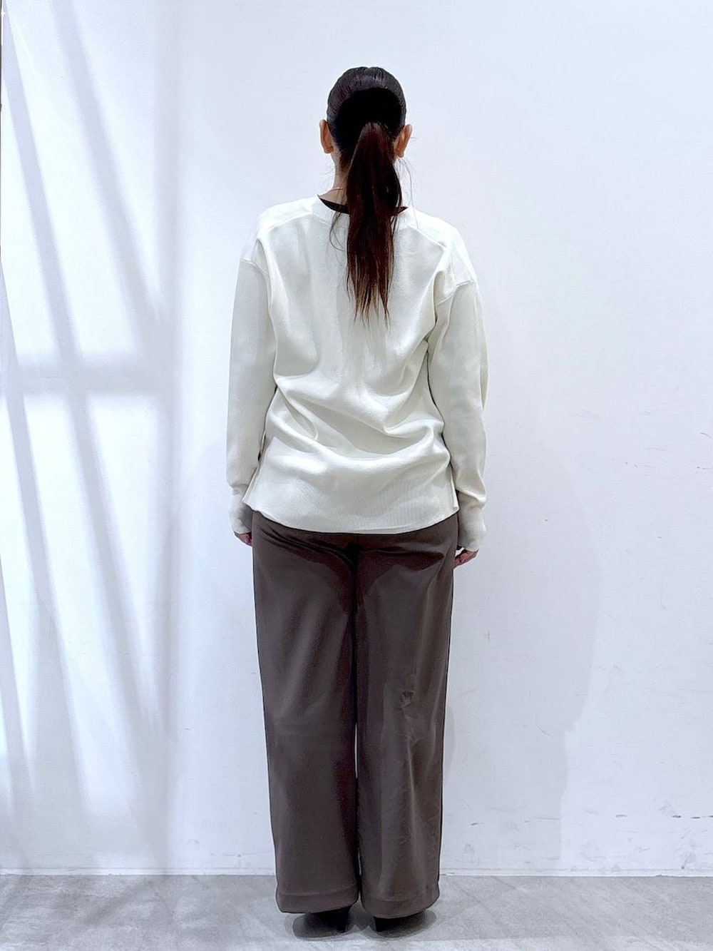 ホワイト系のカーディガン/ボレロ、ブラウン系のその他パンツ、ブラック系のハンドバッグを着用したレディースの冬コーディネートの4枚目の写真