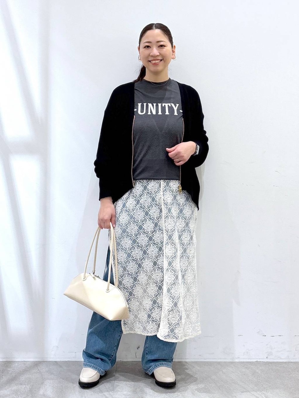 ホワイト系のワンピース、ホワイト系のハンドバッグ、ブルー系のデニムパンツを着用したレディースの春コーディネートの2枚目の写真