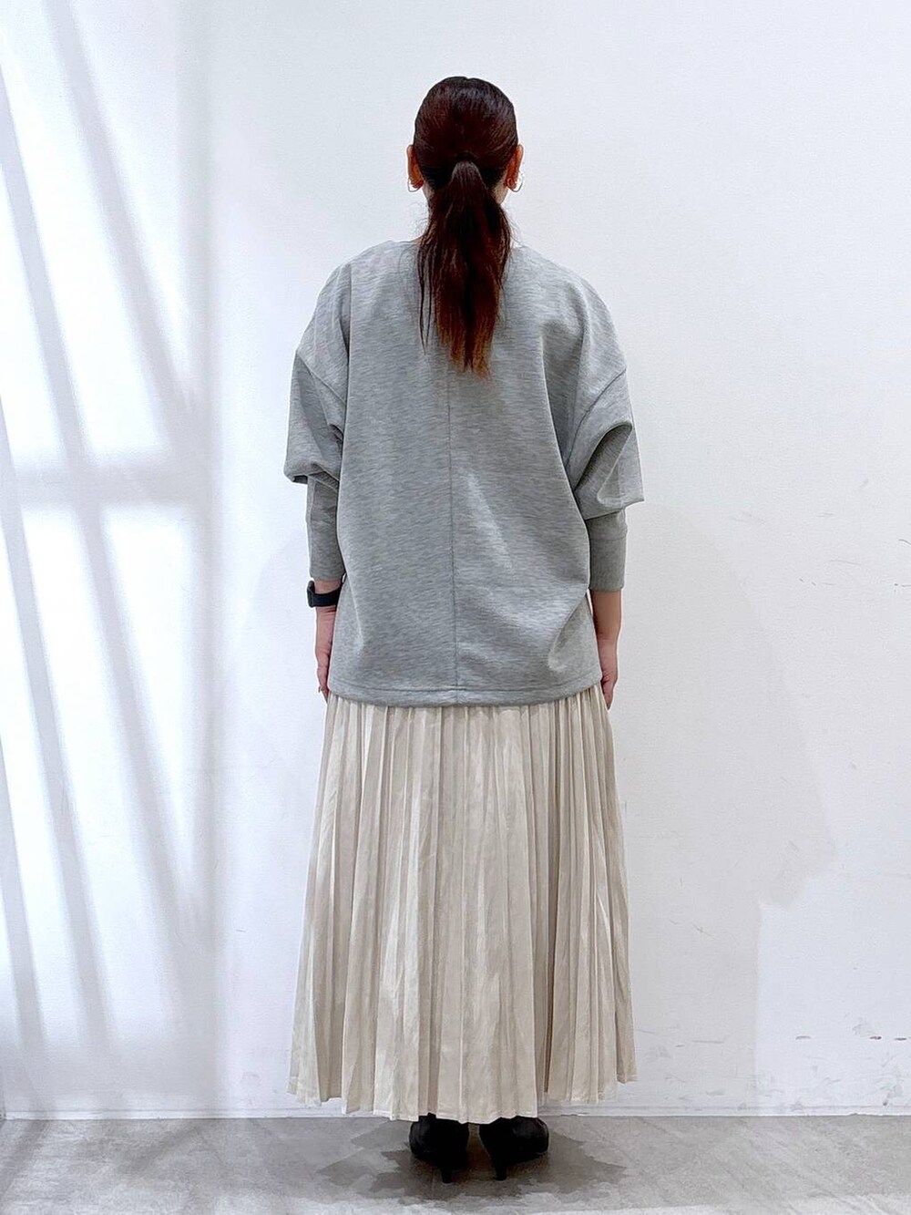 ブラック系のパンプス、グレー系のTシャツ/カットソー、ベージュ系のスカートを着用したレディースの秋コーディネートの3枚目の写真