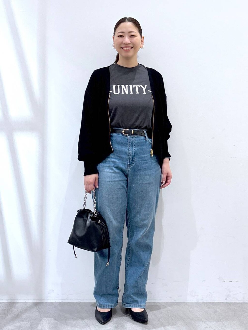 ブルー系のデニムパンツ、ブラック系のカーディガン/ボレロ、グレー系のTシャツ/カットソーを着用したレディースの春コーディネートの2枚目の写真