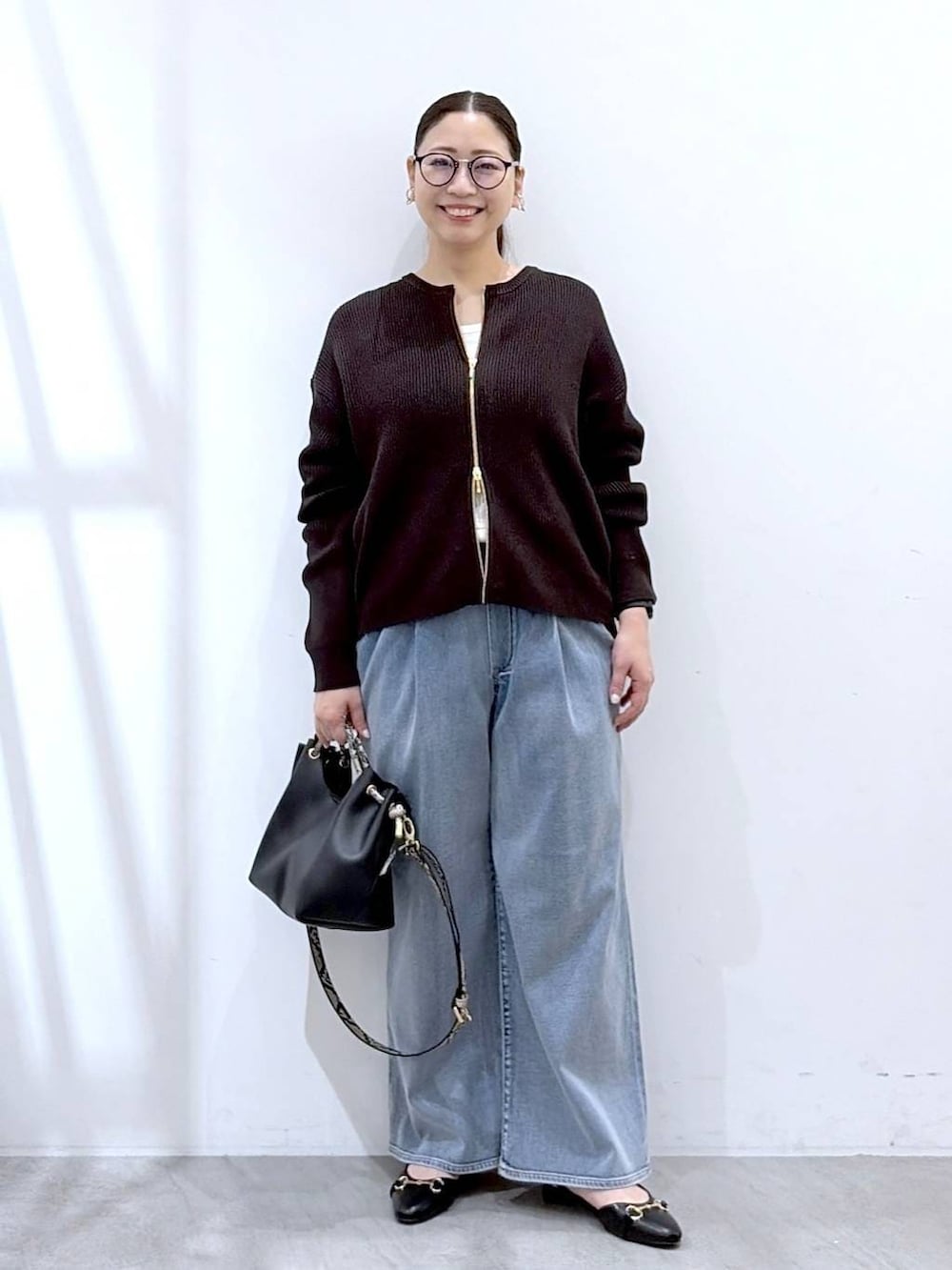 ホワイト系のタンクトップ、ブルー系のデニムパンツ、ブラック系のパンプスを着用したレディースの春コーディネートの2枚目の写真