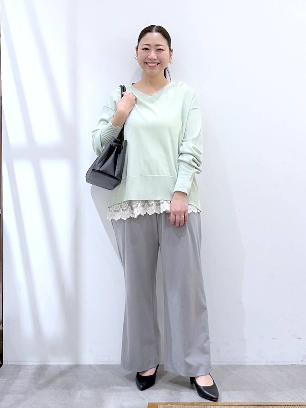 ホワイト系のタンクトップ、ブラック系のハンドバッグ、グレー系のその他パンツを着用したレディースの春コーディネートの2枚目の写真