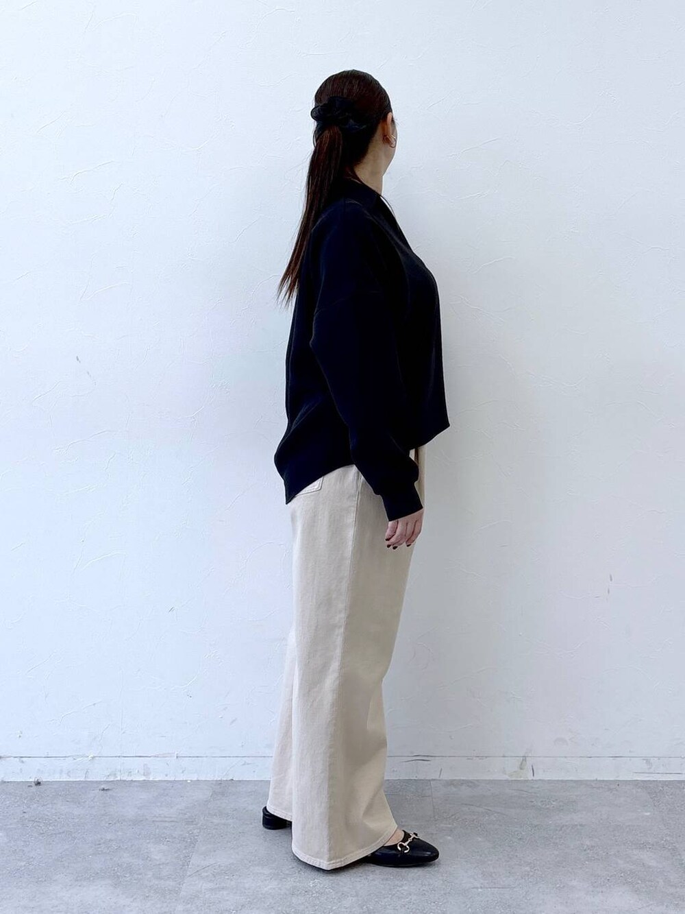 ブラック系のハンドバッグ、ベージュ系のデニムパンツ、ブラック系のパンプスを着用したレディースの冬コーディネートの5枚目の写真