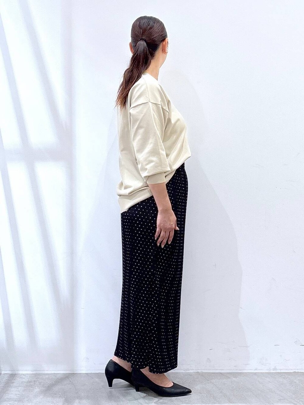 ブラック系のパンプス、ベージュ系のニット/セーター、ブラック系のスカートを着用したレディースの秋コーディネートの5枚目の写真