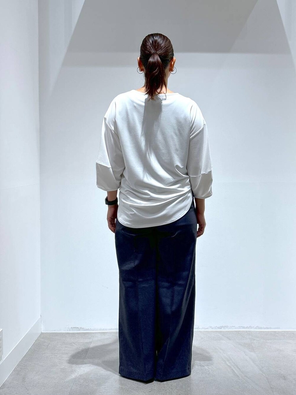 ブラック系のトートバッグ、ブラック系のパンプス、ブルー系のデニムパンツを着用したレディースの秋コーディネートの3枚目の写真