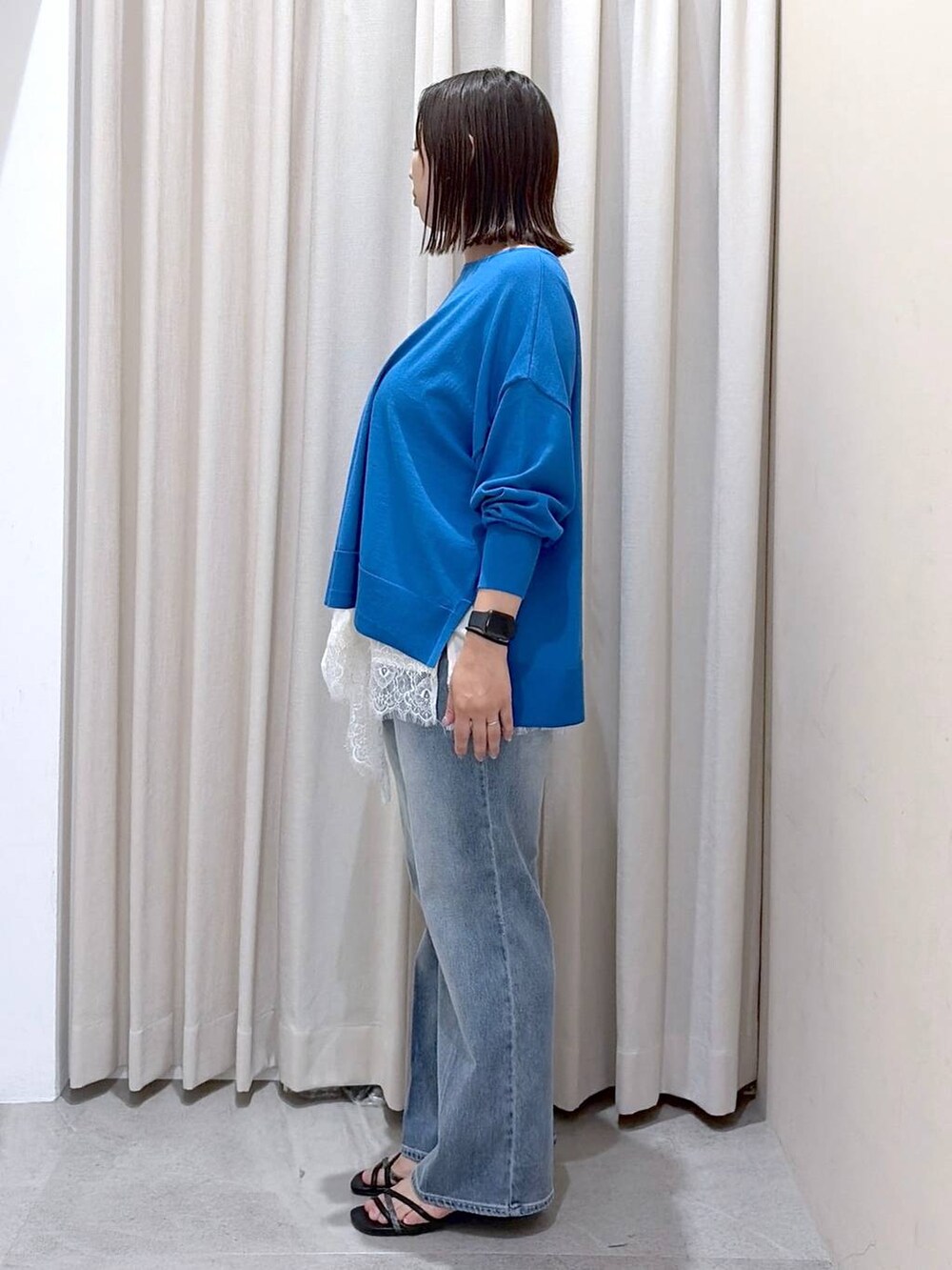 ブルー系のニット/セーター、ホワイト系のキャミソール、ブラック系のハンドバッグを着用したレディースの秋コーディネートの5枚目の写真