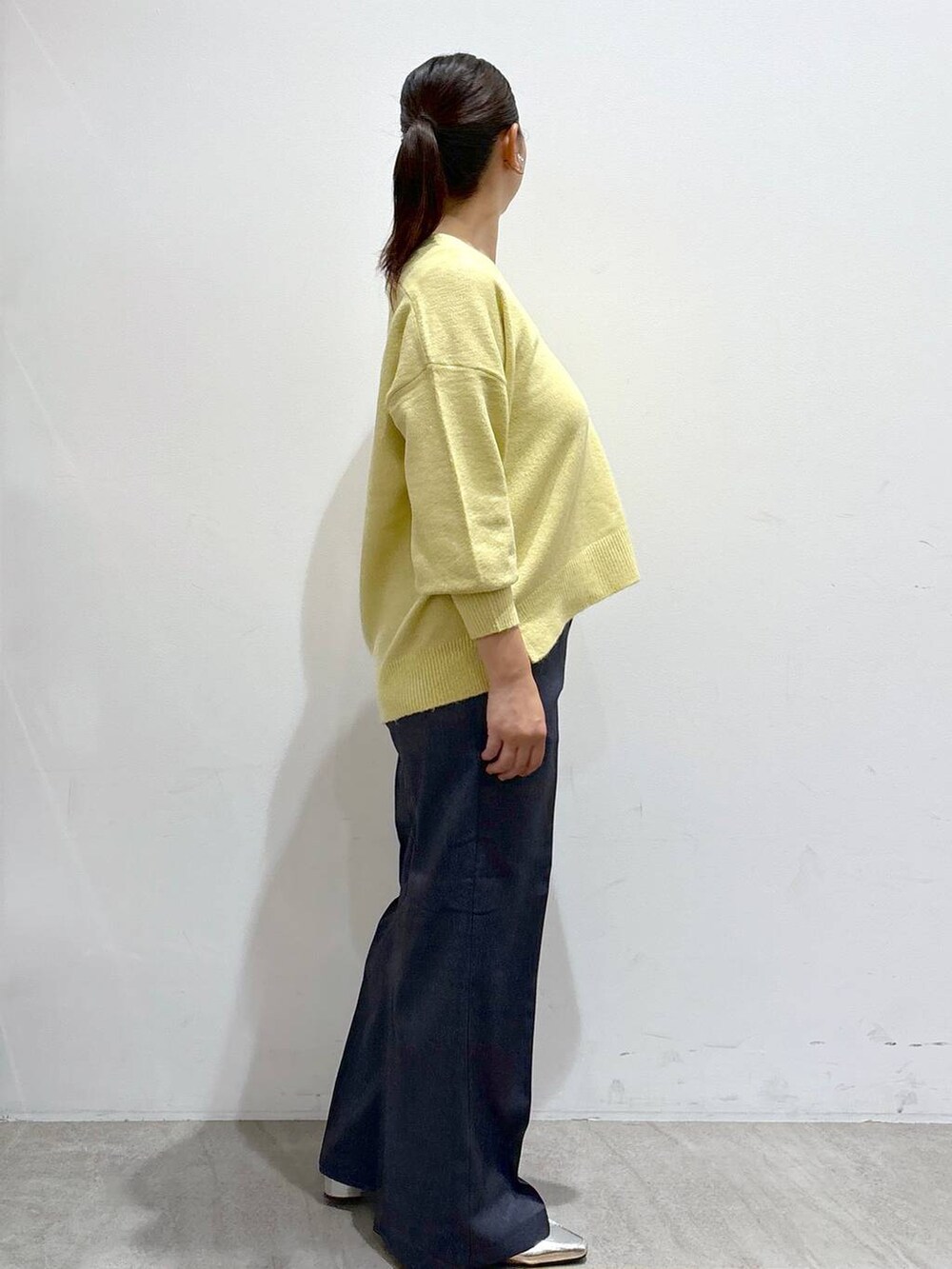 シルバー系のローファー、イエロー系のニット/セーター、ブルー系のデニムパンツを着用したレディースの秋コーディネートの5枚目の写真