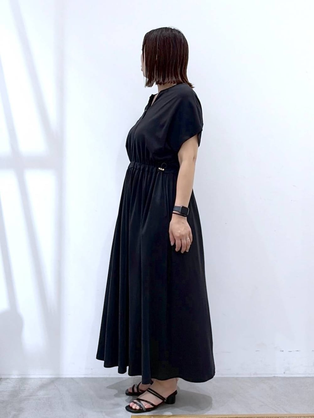 ブラック系のワンピース、ブラック系のサンダル、ブラック系のトートバッグを着用したレディースの夏コーディネートの3枚目の写真
