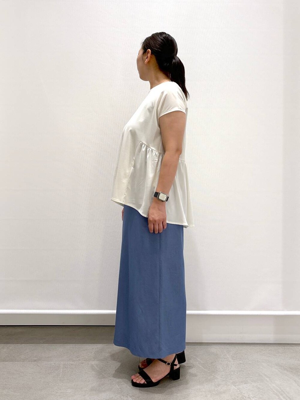 ブラック系のトートバッグ、ブラック系のサンダル、ブルー系のデニムスカートを着用したレディースの夏コーディネートの3枚目の写真