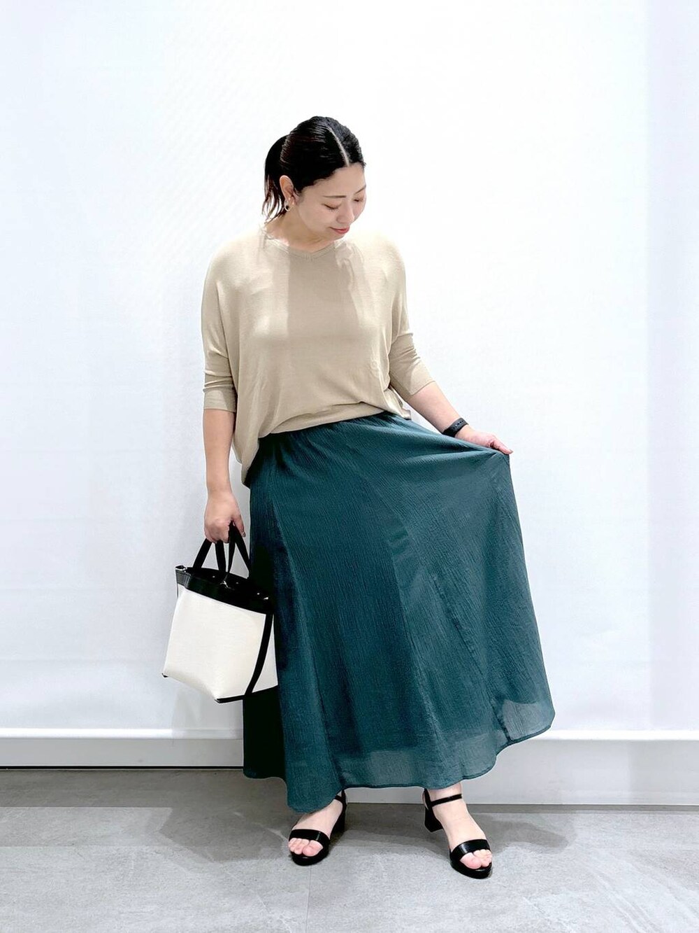 ブラック系のトートバッグ、ブラック系のサンダル、グリーン系のスカートを着用したレディースの夏コーディネートの2枚目の写真