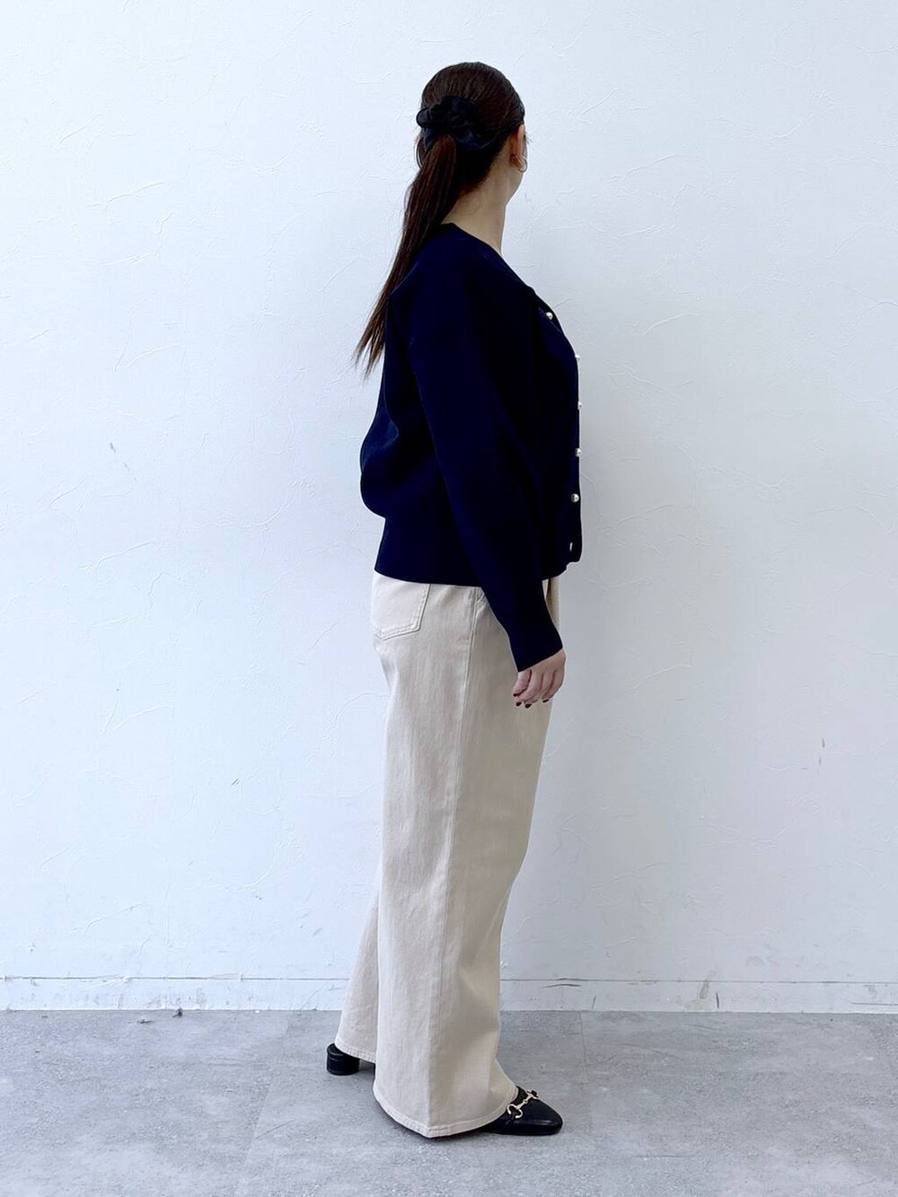 ブラック系のハンドバッグ、ベージュ系のデニムパンツ、ブラック系のパンプスを着用したレディースの冬コーディネートの5枚目の写真