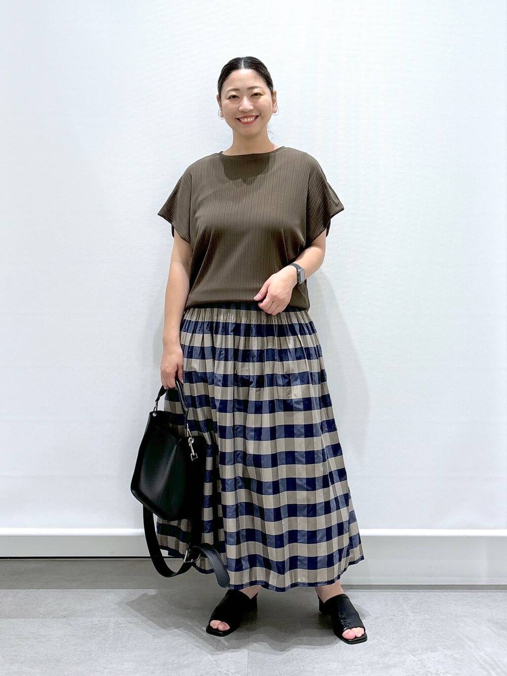 ブラック系のサンダル、グリーン系のTシャツ/カットソー、グリーン系のスカートを着用したレディースの夏コーディネートの2枚目の写真