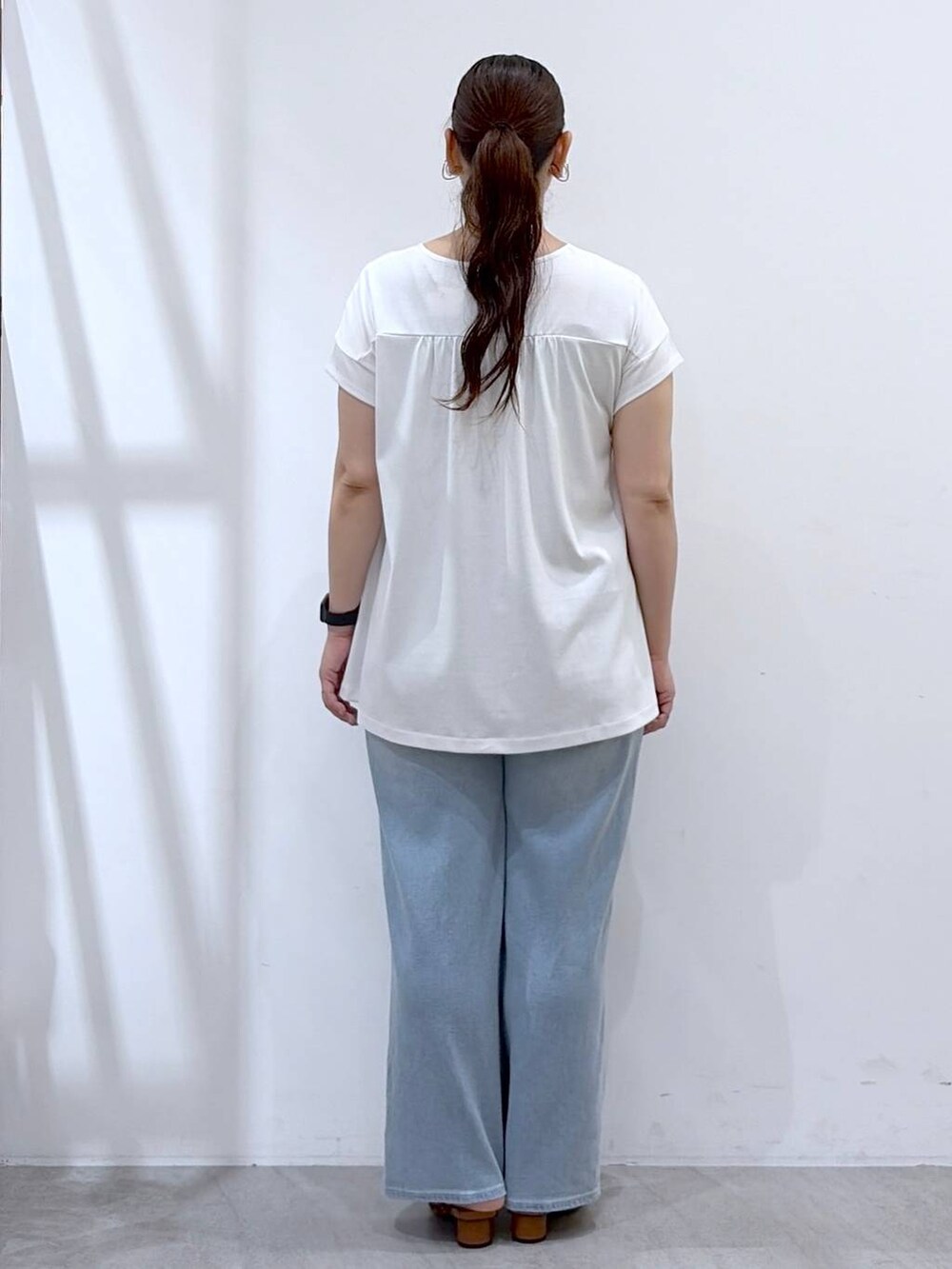 ブラウン系のサンダル、ブラウン系のハンドバッグ、ホワイト系のTシャツ/カットソーを着用したレディースの夏コーディネートの4枚目の写真