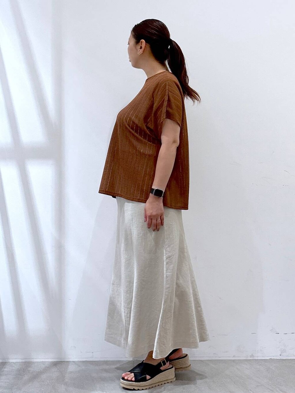 ベージュ系のスカート、ブラック系のハンドバッグ、ブラウン系のTシャツ/カットソーを着用したレディースの夏コーディネートの3枚目の写真