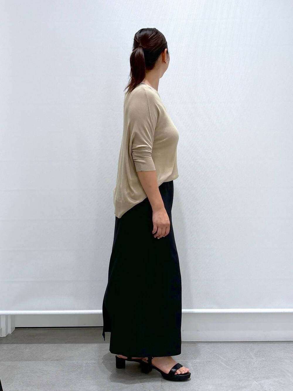 ブラック系のサンダル、ベージュ系のニット/セーター、ブラック系のスカートを着用したレディースの秋コーディネートの5枚目の写真