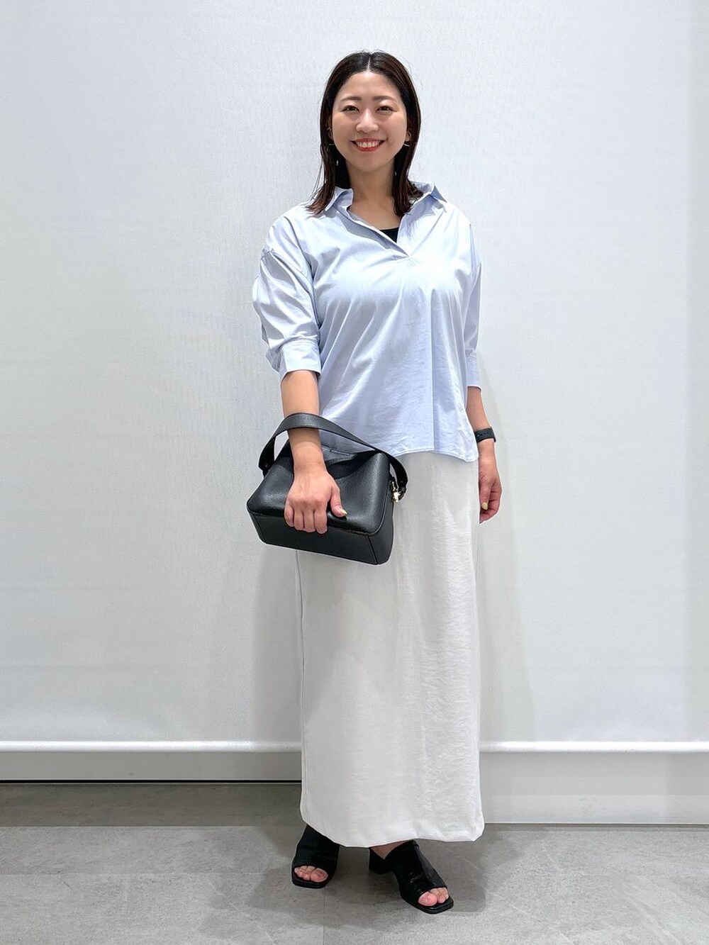 ブラック系のサンダル、ブラック系のハンドバッグ、ブルー系のシャツ/ブラウスを着用したレディースの夏コーディネートの2枚目の写真