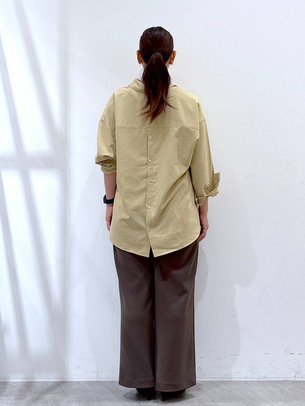 ブラック系のパンプス、イエロー系のシャツ/ブラウス、ブラック系のハンドバッグを着用したレディースの秋コーディネートの4枚目の写真