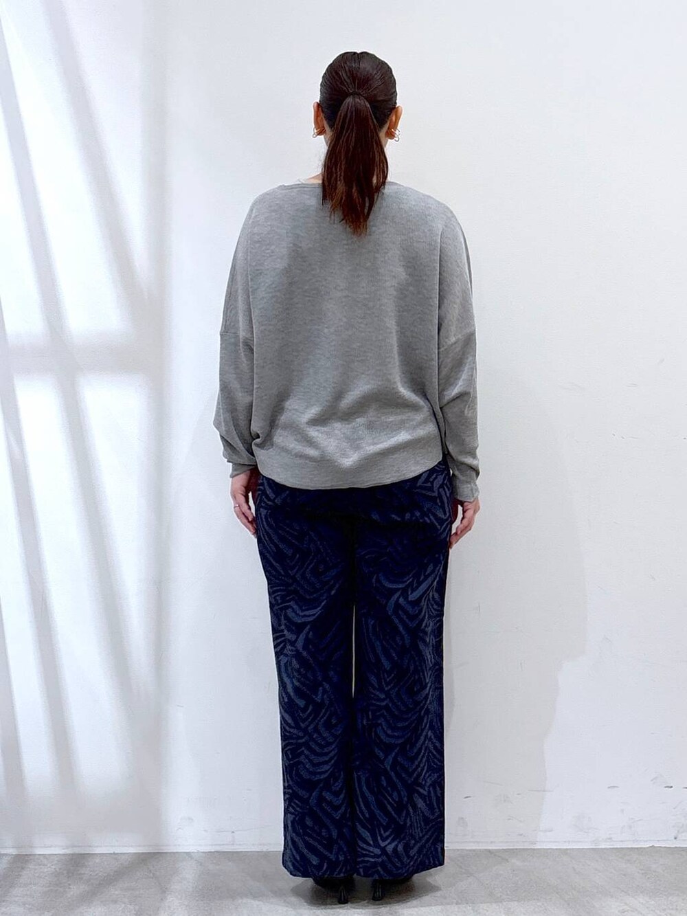 グレー系のニット/セーター、ブルー系のその他パンツ、ブラック系のハンドバッグを着用したレディースの春コーディネートの4枚目の写真