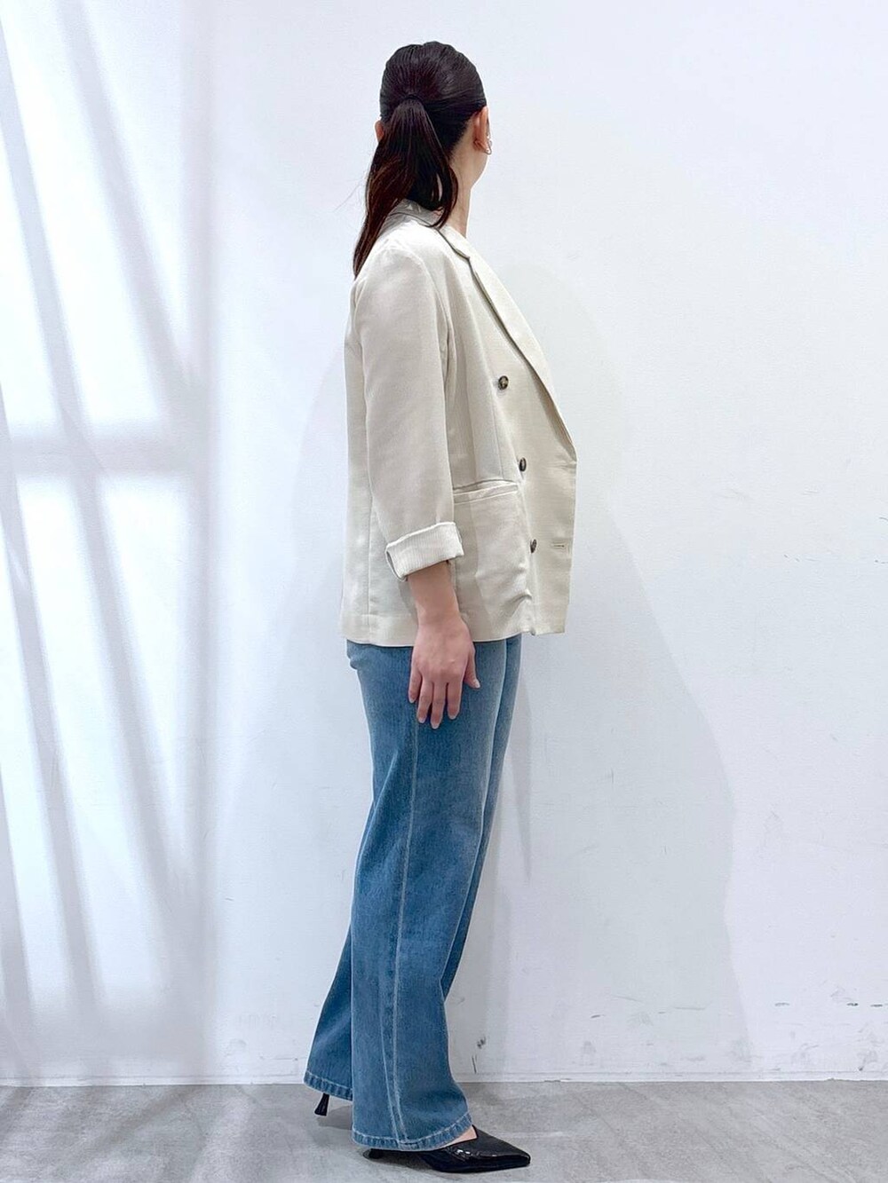 ブルー系のデニムパンツ、ベージュ系のテーラードジャケット、ホワイト系のタンクトップを着用したレディースの春コーディネートの5枚目の写真