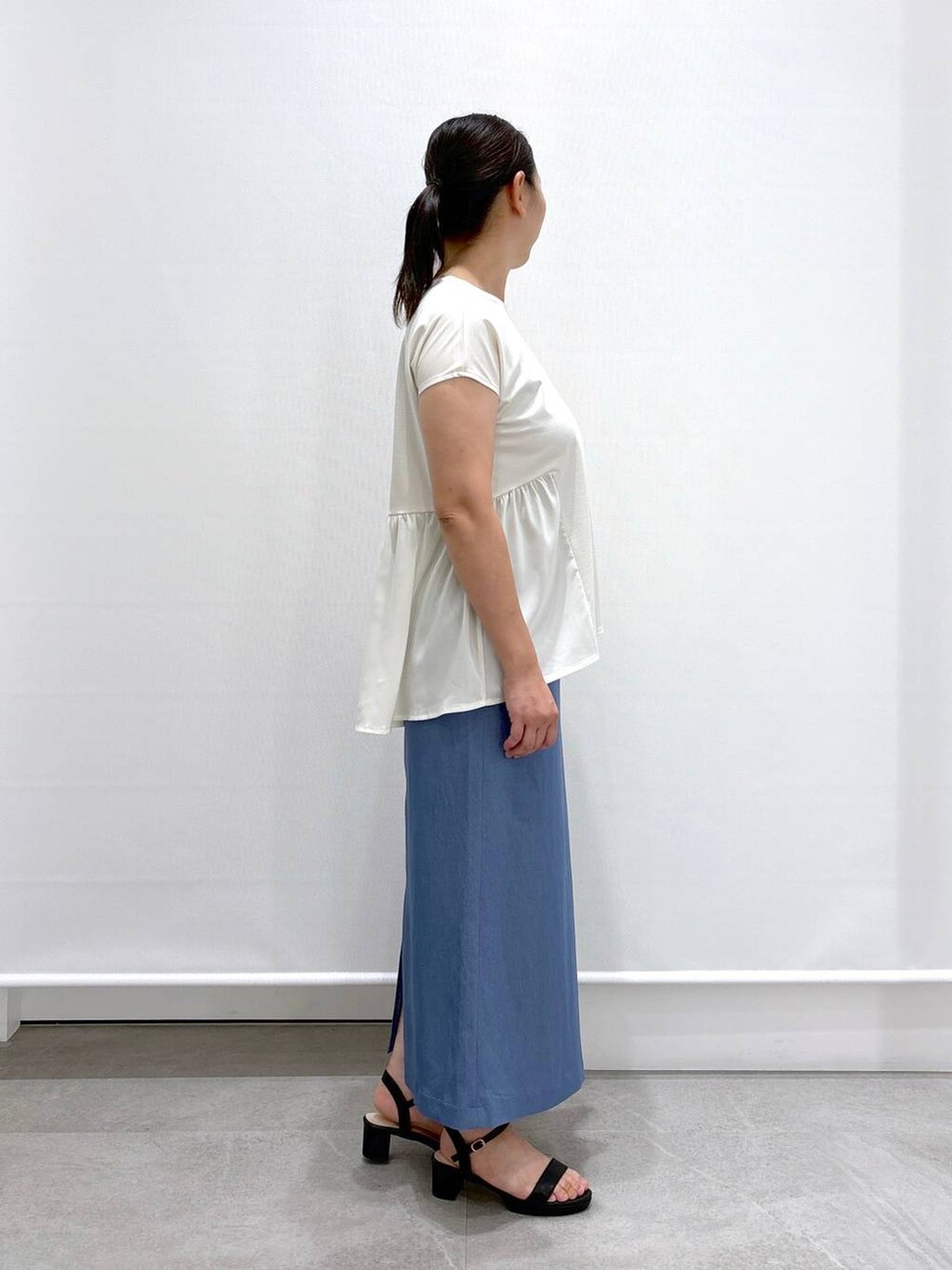 ブラック系のトートバッグ、ブラック系のサンダル、ブルー系のデニムスカートを着用したレディースの夏コーディネートの5枚目の写真