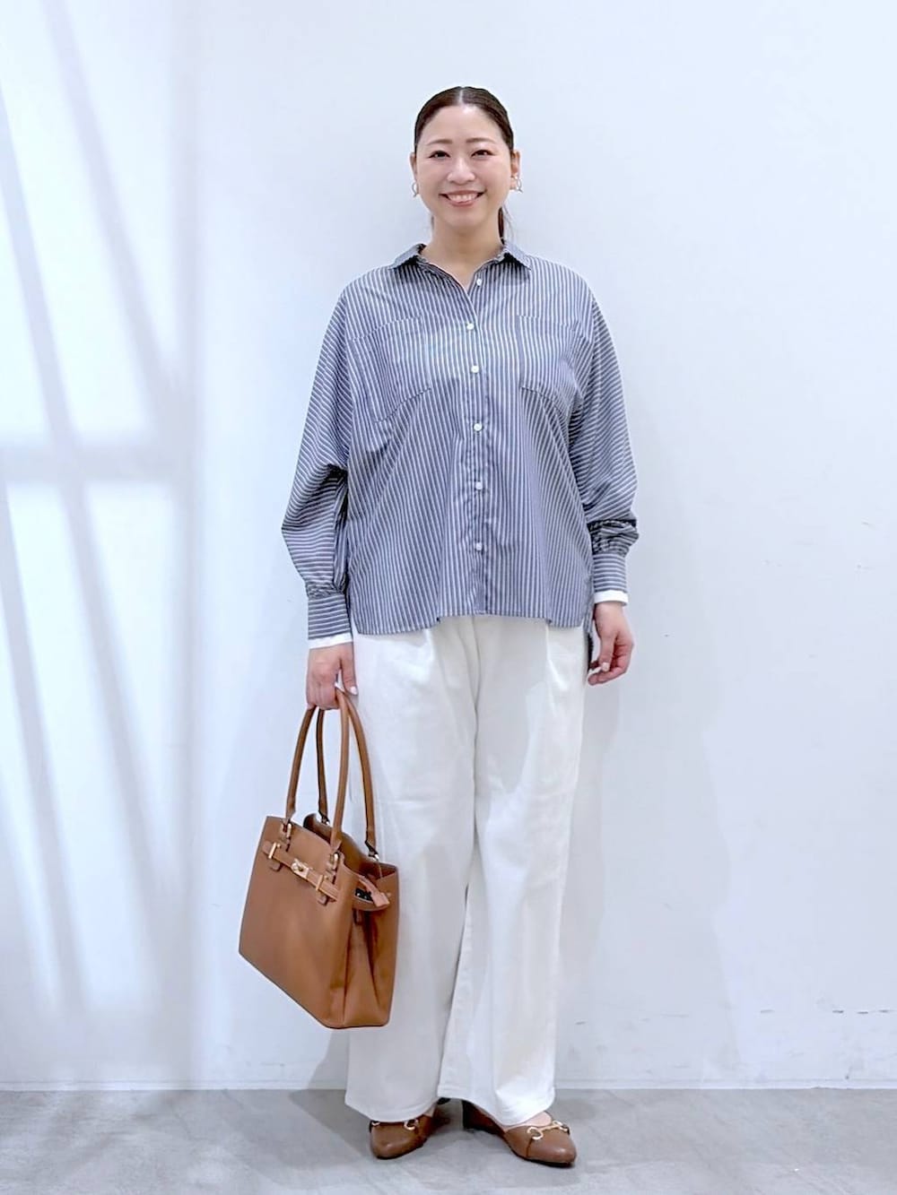 ホワイト系のデニムパンツ、イエロー系のハンドバッグ、ブルー系のシャツ/ブラウスを着用したレディースの春コーディネートの2枚目の写真