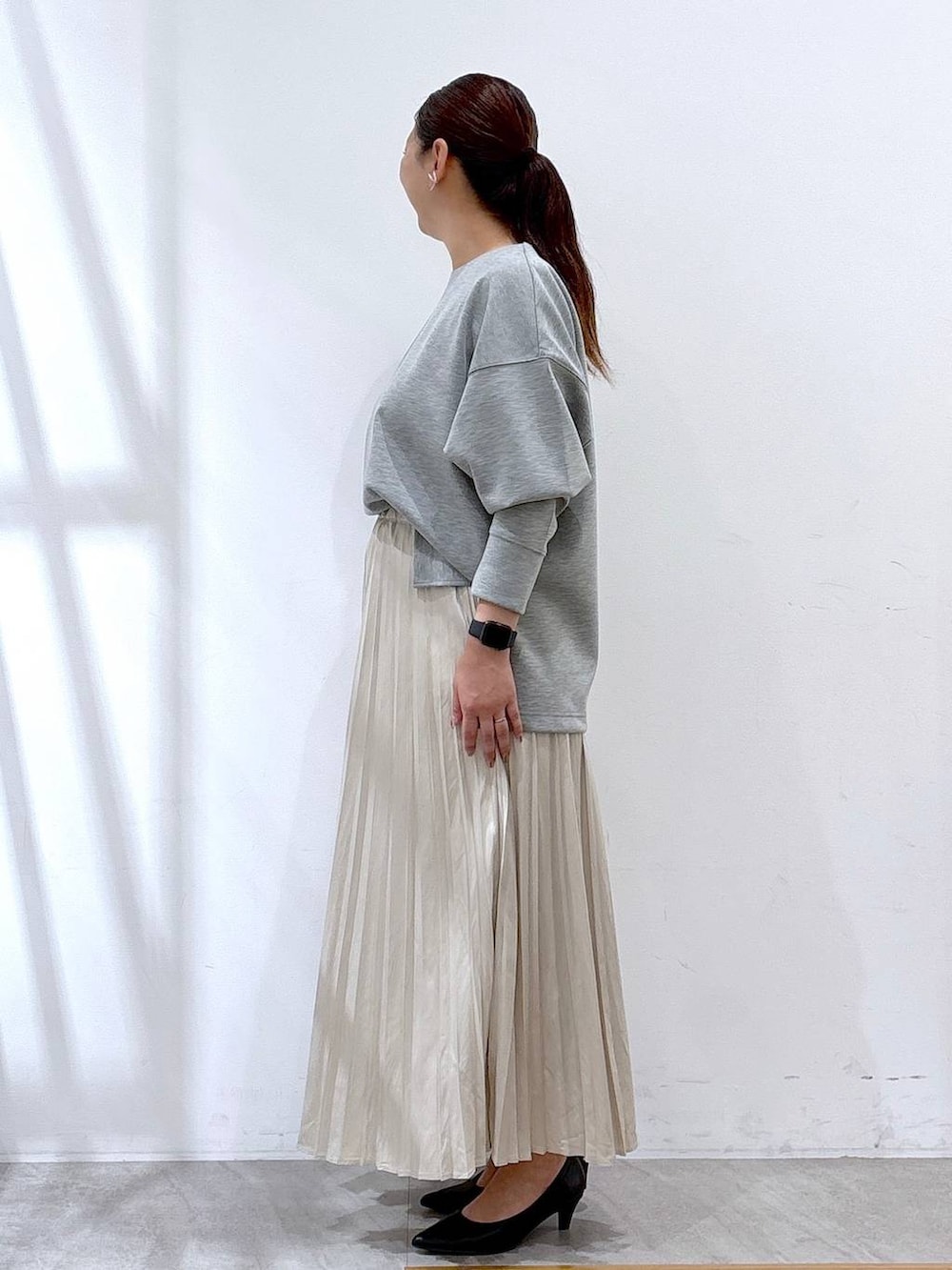 ブラック系のパンプス、グレー系のTシャツ/カットソー、ベージュ系のスカートを着用したレディースの秋コーディネートの2枚目の写真