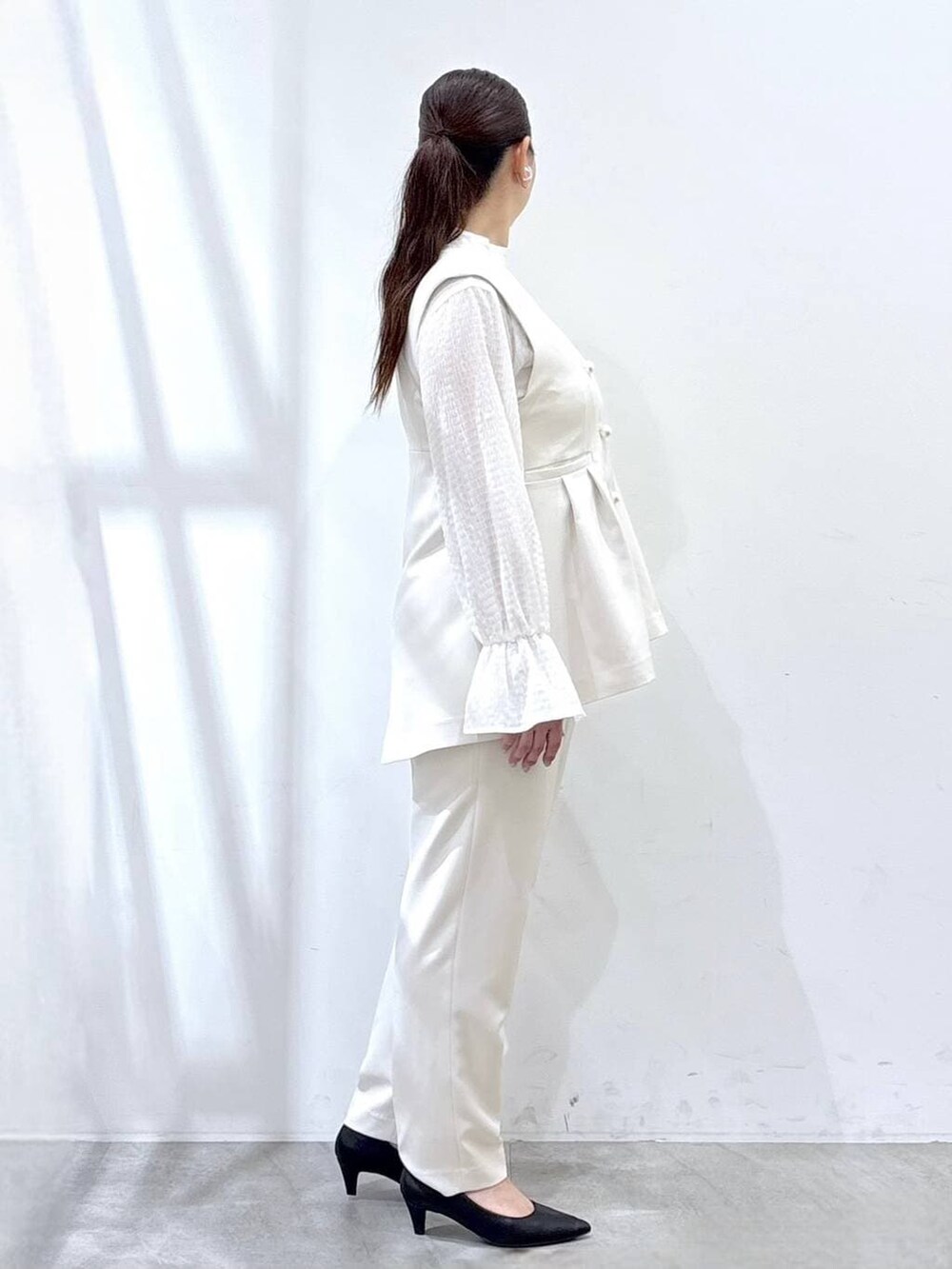 ブラック系のハンドバッグ、ホワイト系のシャツ/ブラウス、ホワイト系のベストを着用したレディースの冬コーディネートの5枚目の写真