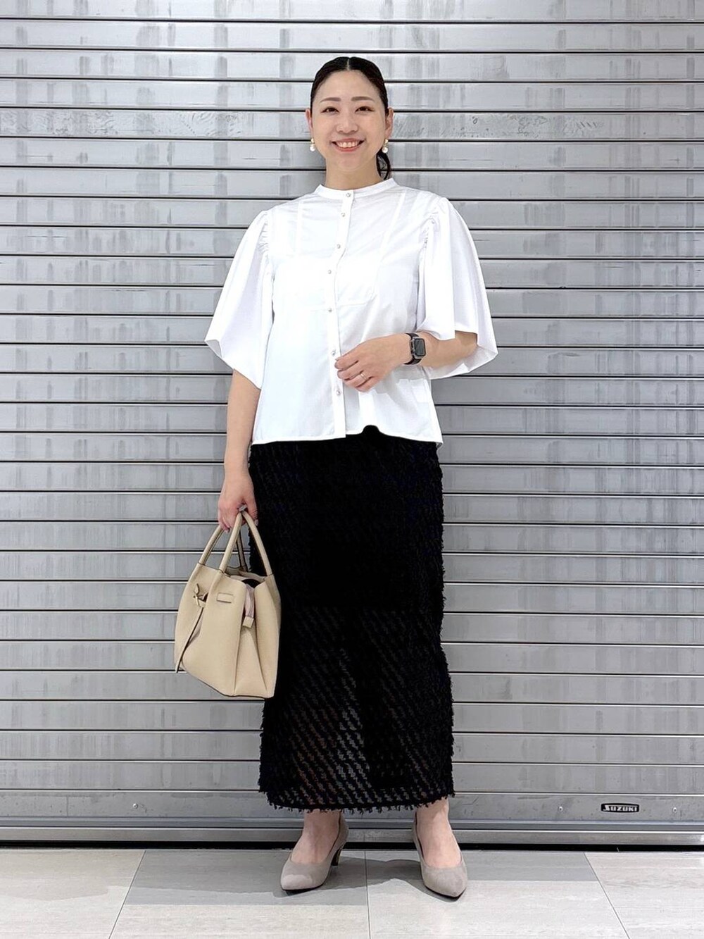 ベージュ系のパンプス、ベージュ系のハンドバッグを着用したレディースの春コーディネートの2枚目の写真