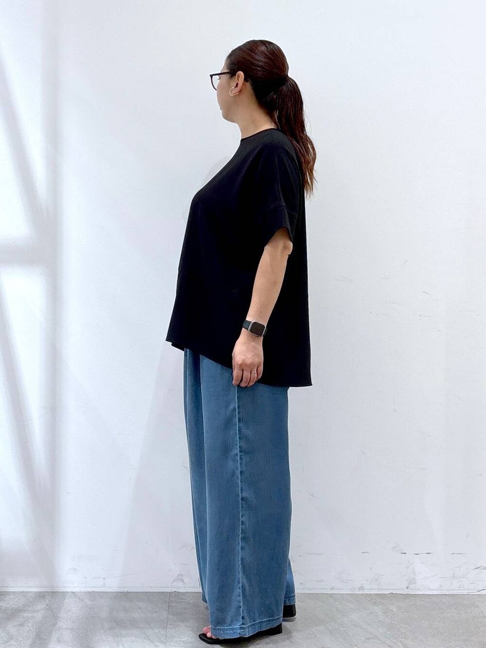 ブラック系のシャツ/ブラウス、ブラック系のサンダル、ブルー系のデニムパンツを着用したレディースの夏コーディネートの3枚目の写真