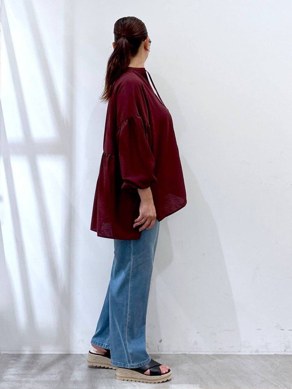 ブラック系のハンドバッグ、ブラック系のサンダル、ブルー系のデニムパンツを着用したレディースの夏コーディネートの4枚目の写真