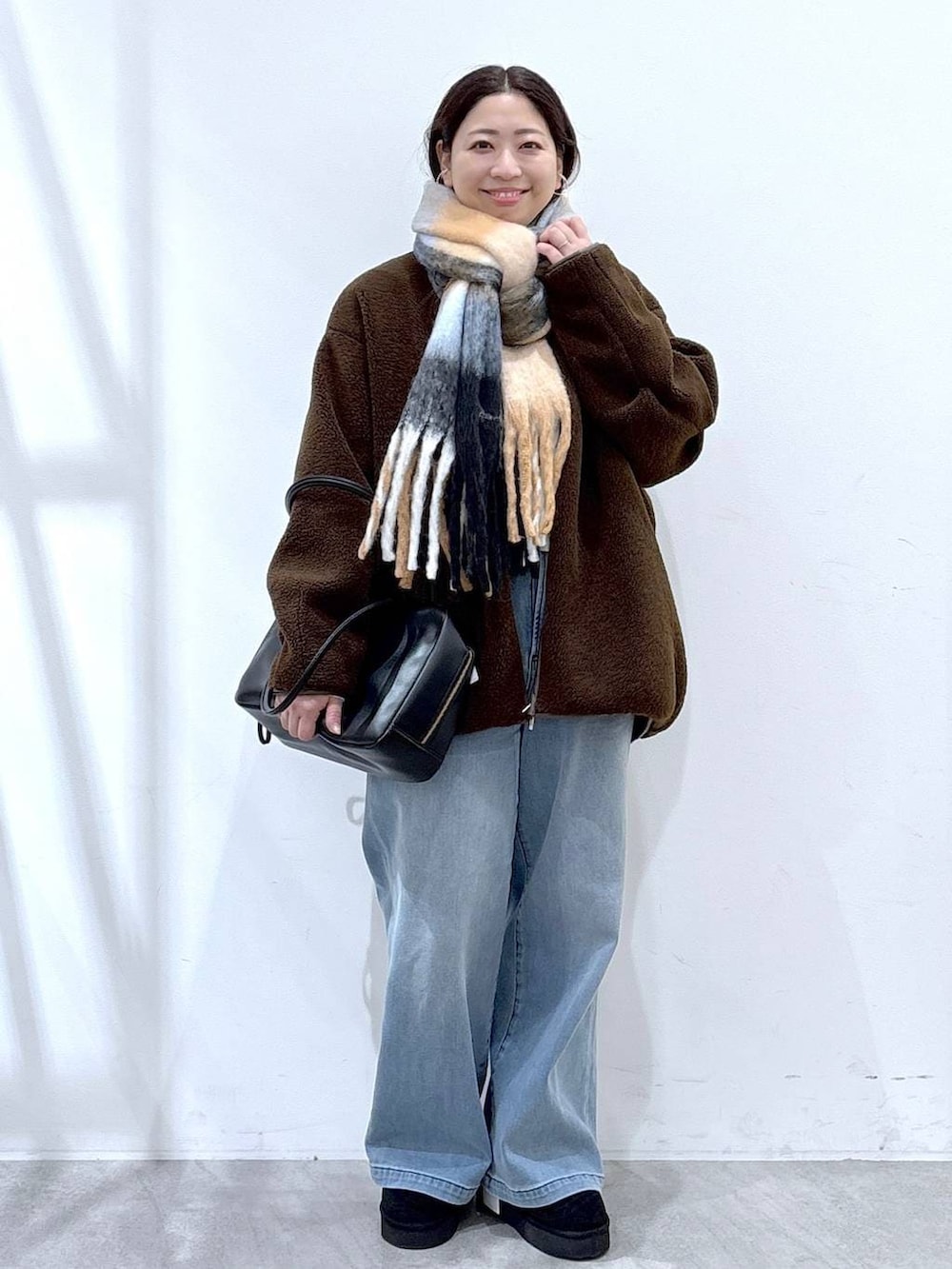 ブラック系のブーツ、ブラック系のボストンバッグ、ブラウン系のブルゾンを着用したレディースの冬コーディネートの2枚目の写真