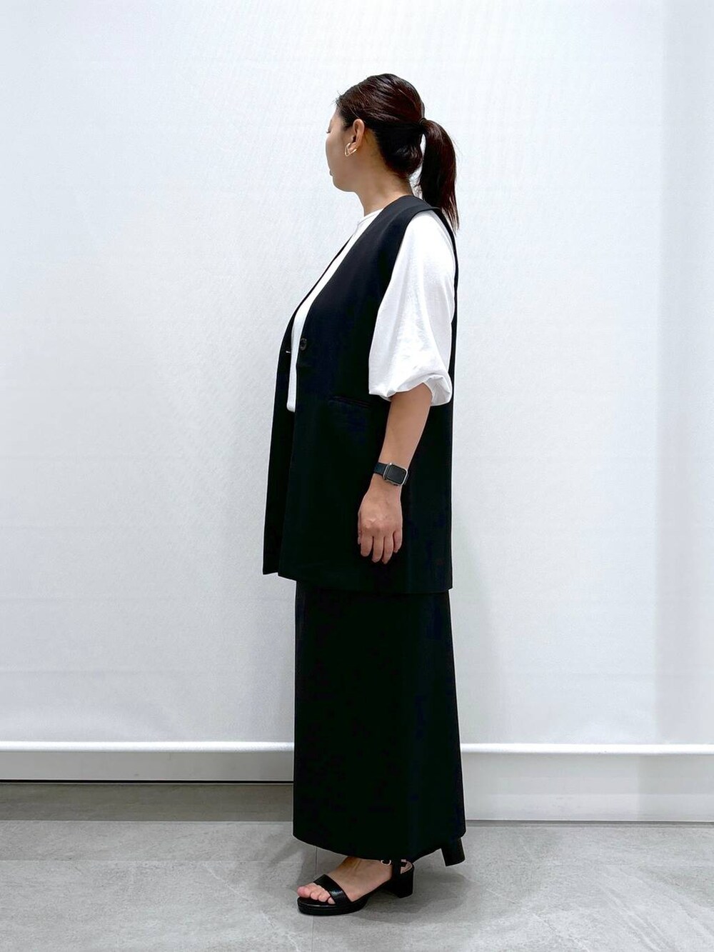 ブラック系のトートバッグ、ブラック系のサンダル、ブラック系のスカートを着用したレディースの秋コーディネートの3枚目の写真