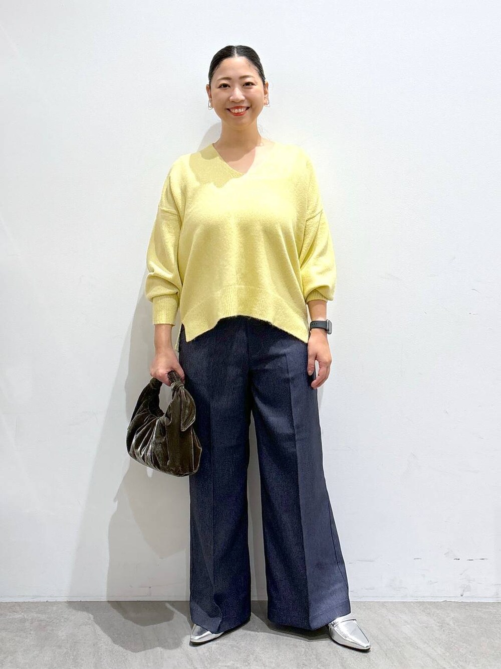 シルバー系のローファー、イエロー系のニット/セーター、ブルー系のデニムパンツを着用したレディースの秋コーディネートの2枚目の写真