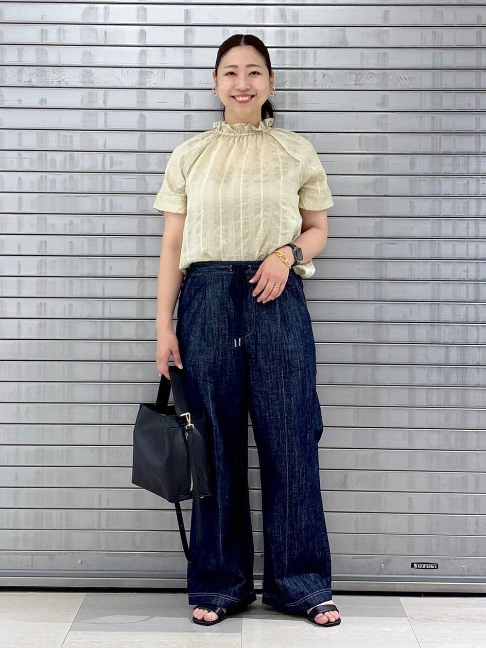 ブルー系のデニムパンツ、ブラック系のハンドバッグ、ホワイト系のシャツ/ブラウスを着用したレディースの夏コーディネートの2枚目の写真