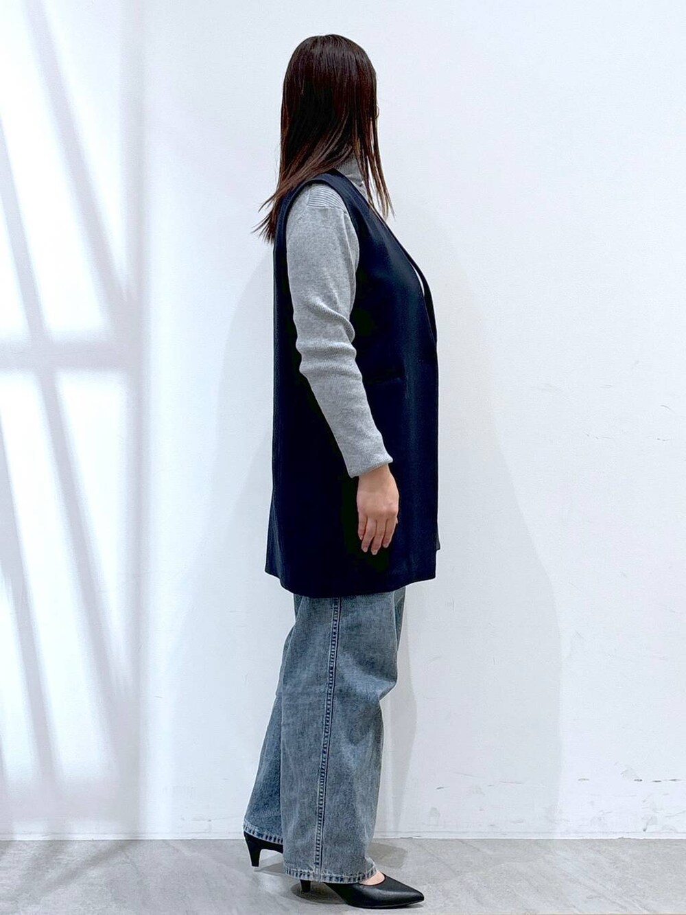 ブルー系のデニムパンツ、グレー系のニット/セーター、ブルー系のスーツベストを着用したレディースの冬コーディネートの5枚目の写真