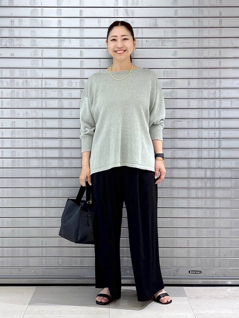 ブラック系のハンドバッグ、ブラック系のその他パンツ、グリーン系のニット/セーターを着用したレディースの春コーディネートの2枚目の写真