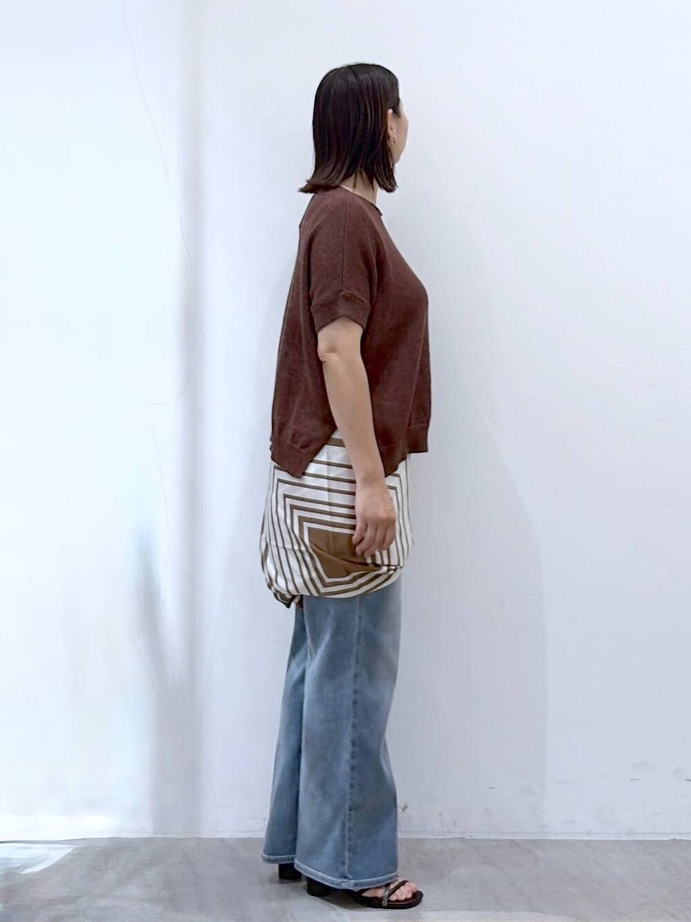 ブラック系のサンダル、ブルー系のデニムパンツ、ブラウン系のストール/ショールを着用したレディースの秋コーディネートの5枚目の写真