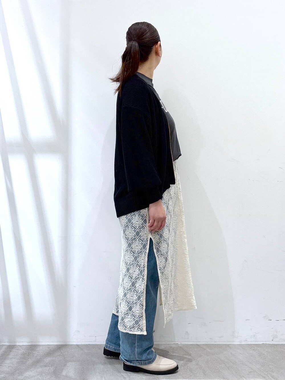 ホワイト系のワンピース、ホワイト系のハンドバッグ、ブルー系のデニムパンツを着用したレディースの春コーディネートの5枚目の写真