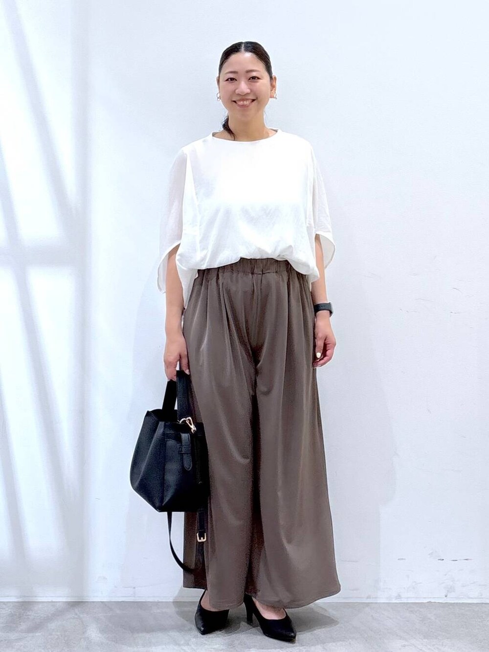 ブラック系のパンプス、ホワイト系のTシャツ/カットソー、ブラック系のハンドバッグを着用したレディースの夏コーディネートの2枚目の写真