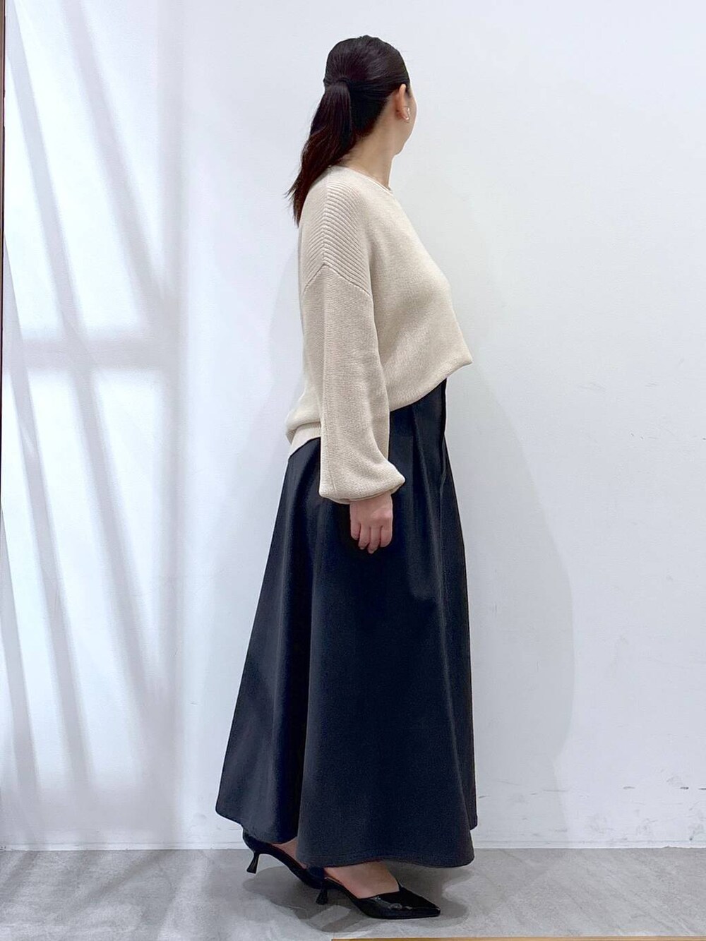 ホワイト系のニット/セーター、グレー系のスカートを着用したレディースの春コーディネートの5枚目の写真